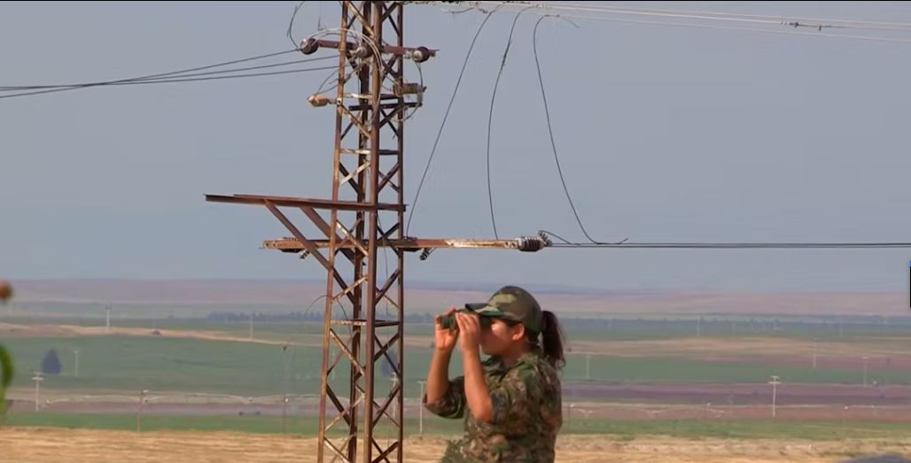 Combattente curda dello Ypj di guardia con binocolo